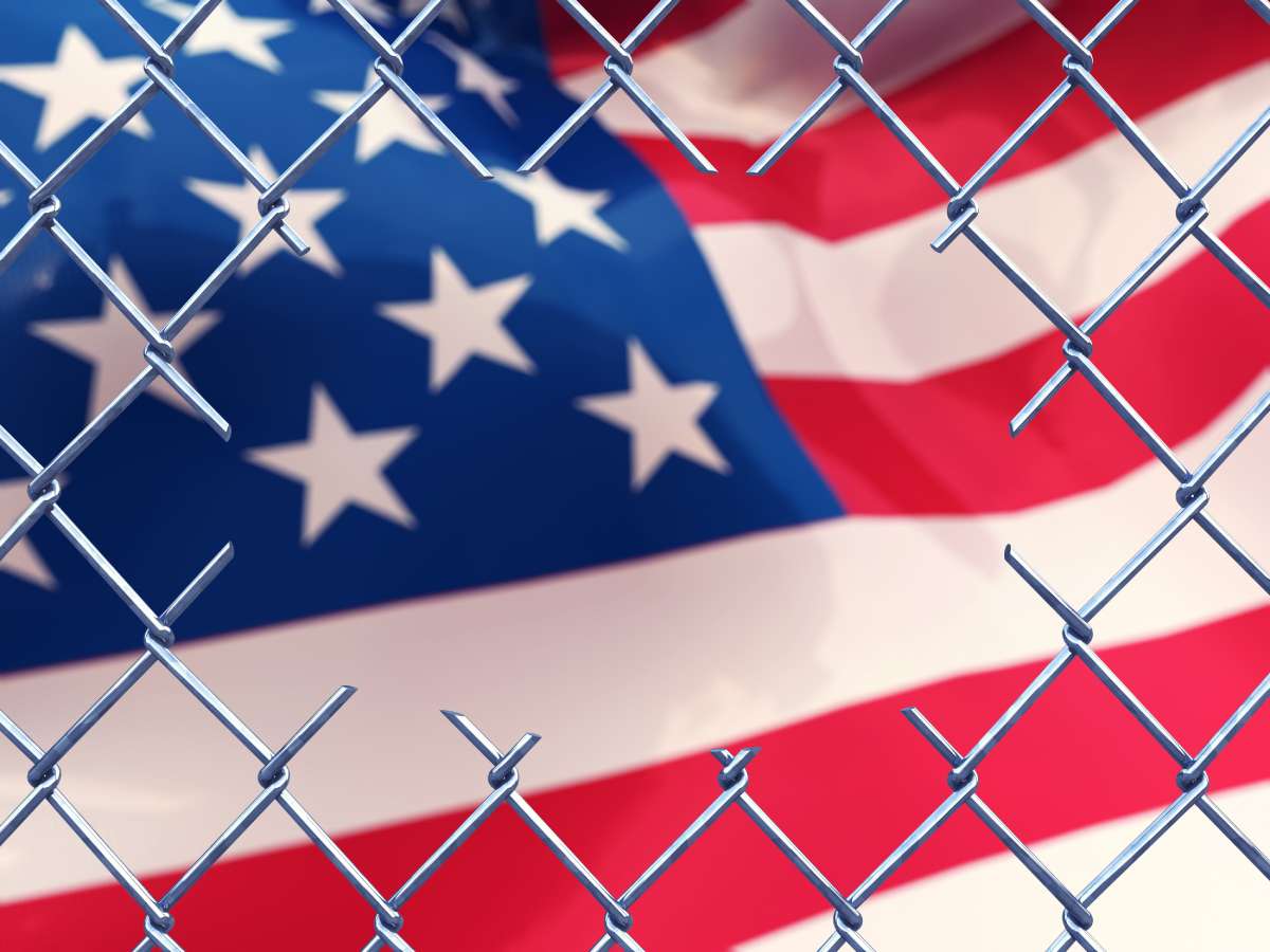 USA flag with broken wire fence infront of it 