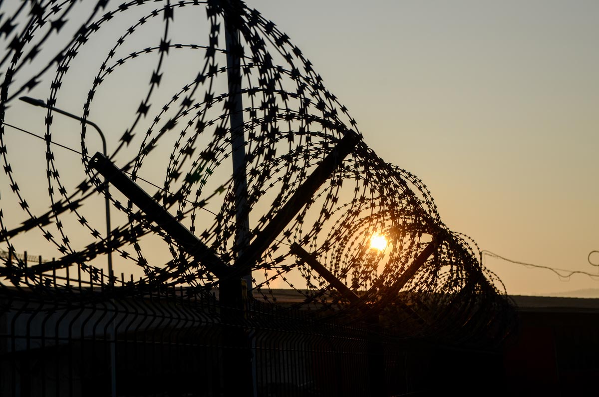 Close-up of sharp razor wire fence at sunset