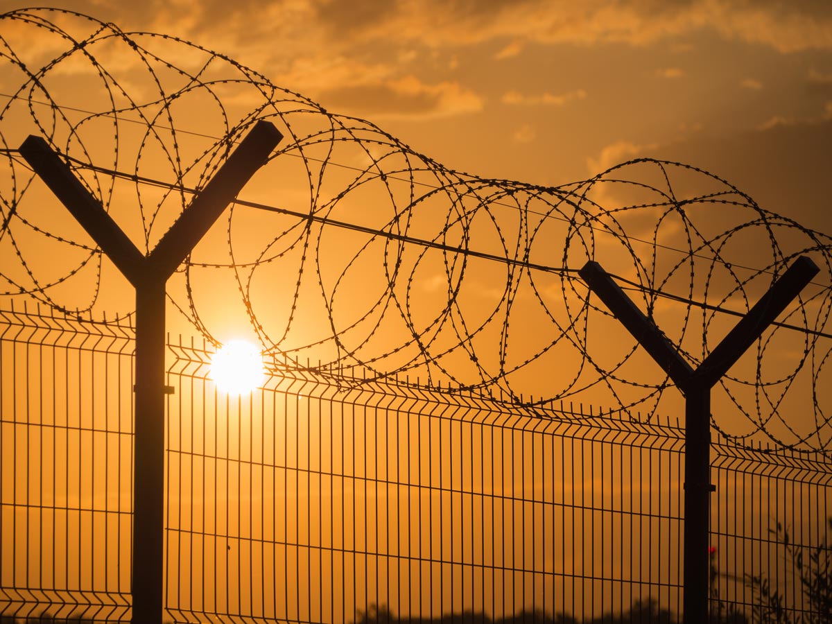 Razor wire against a bright sunset
