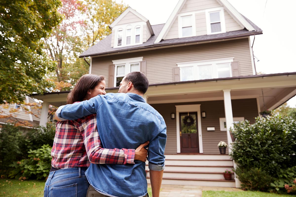 Couple embracing in front of new home