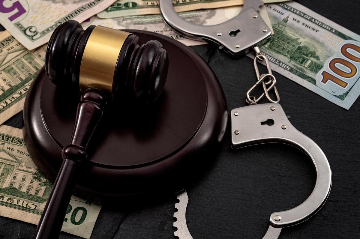 Gavel, handcuffs and money scattered on a dark background