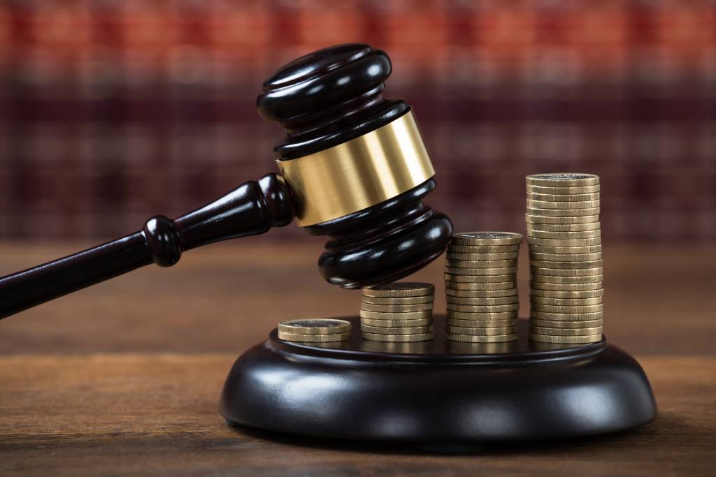 Closeup of mallet being hit on stacked coins at table in courtroom