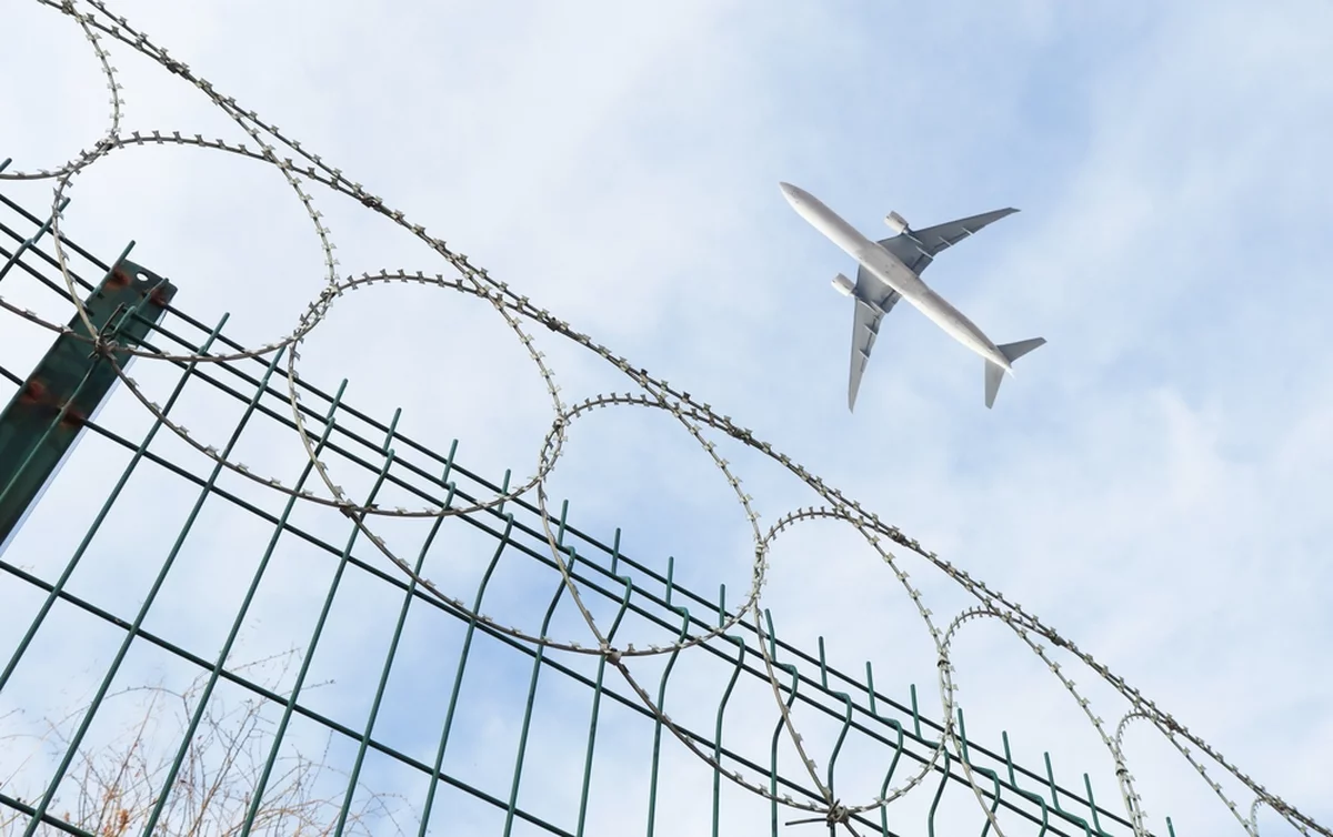 Passenger plane flying over metal barbed wire