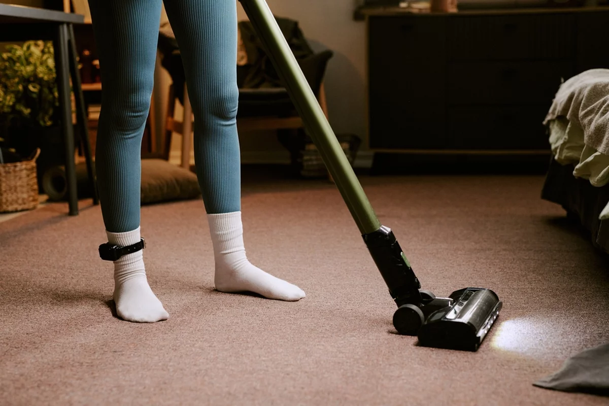 Woman with ankle monitor vacuuming
